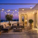 Terraza moderna decorada con guirnaldas de luces LED solares de estilo vintage al atardecer, creando un ambiente acogedor y chill-out.